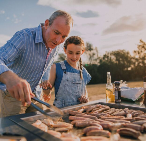 Father and daughter grilling sausages